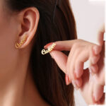 Woman wearing a custom name earring in 18K gold script font.