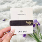 Side view of a custom oval metal logo plate attached to a burgundy velvet headband.