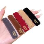 Close-up of a beige faux fur headband featuring a custom metal brand tag.