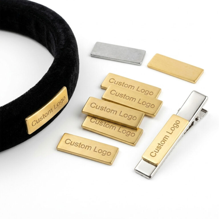 Custom metal logo for hair accessories featuring engraved zinc alloy brand tags on a velvet headband and hair clip with a pure white background.