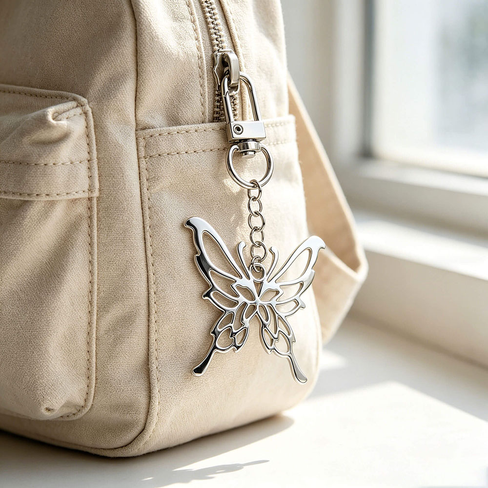 Fashion bag pendant in a butterfly shape attached to a canvas backpack to demonstrate real-world handbag hardware application.
