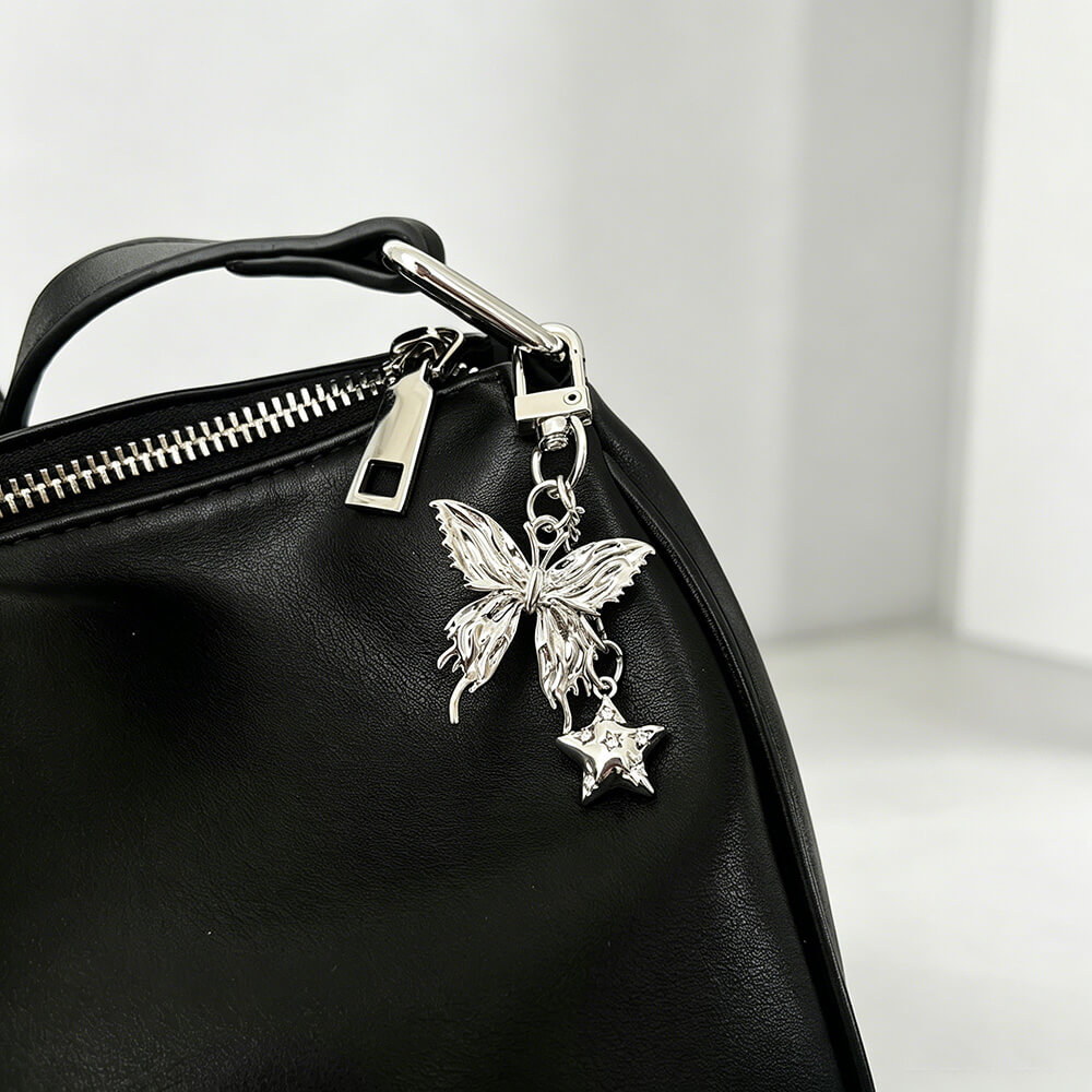 Luxury brand handbag hardware charm butterfly bag charm attached to a premium black leather purse