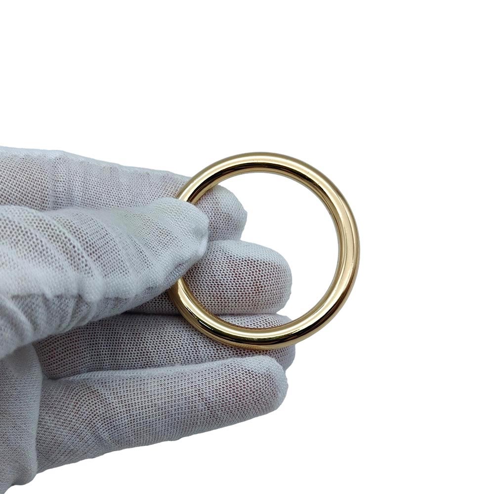 Gold O ring handbag hardware held by gloved hand for supplier evaluation