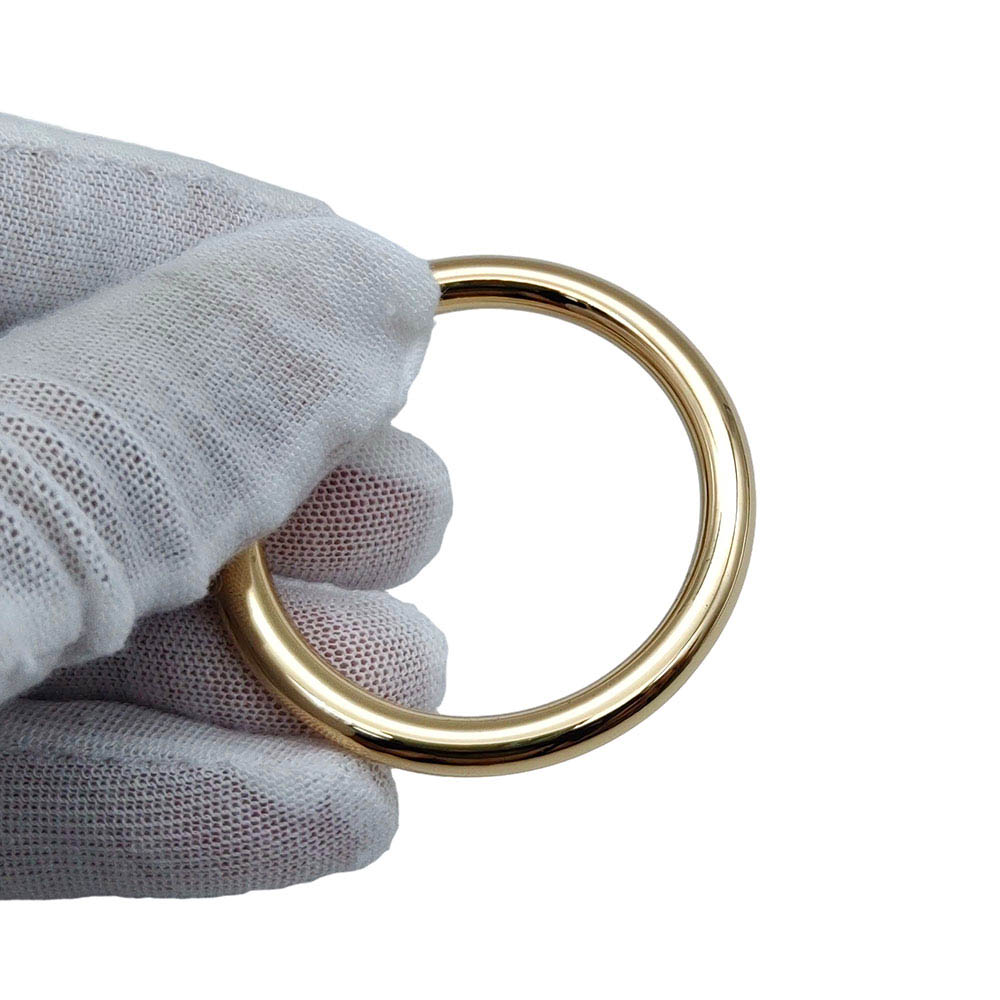 Gloved hand holding gold zinc alloy O ring during quality inspection
